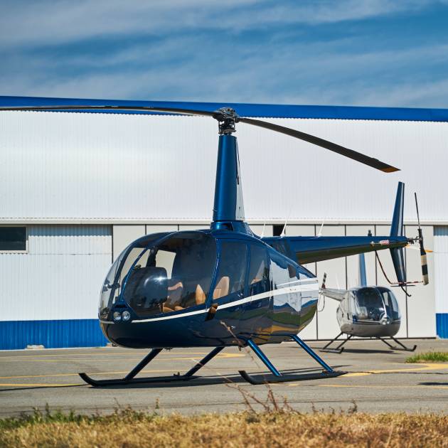 Back view of woman and man with trolley bag walking up to private helicopter