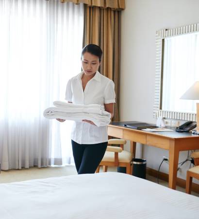 Vietnamese hotel maid changing towels in the room
